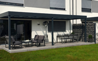 Terrassenüberdachung mit dunklem Aluminiumrahmen an einem modernen Wohnhaus