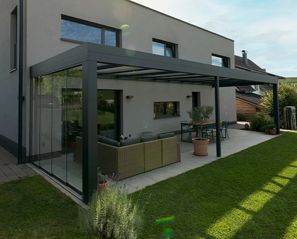 Elegantes Terrassendach aus Aluminium und Glas für stilvolle Outdoor-Lounge und Essbereich im Garten.