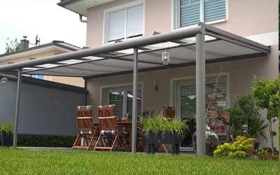 Terrassendach aus dunklem Aluminium mit geschütztem Sitzbereich direkt am Wohnhaus