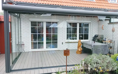 Terrassenüberdachung mit Glasdach und seitlicher Verglasung an einem Wohnhaus