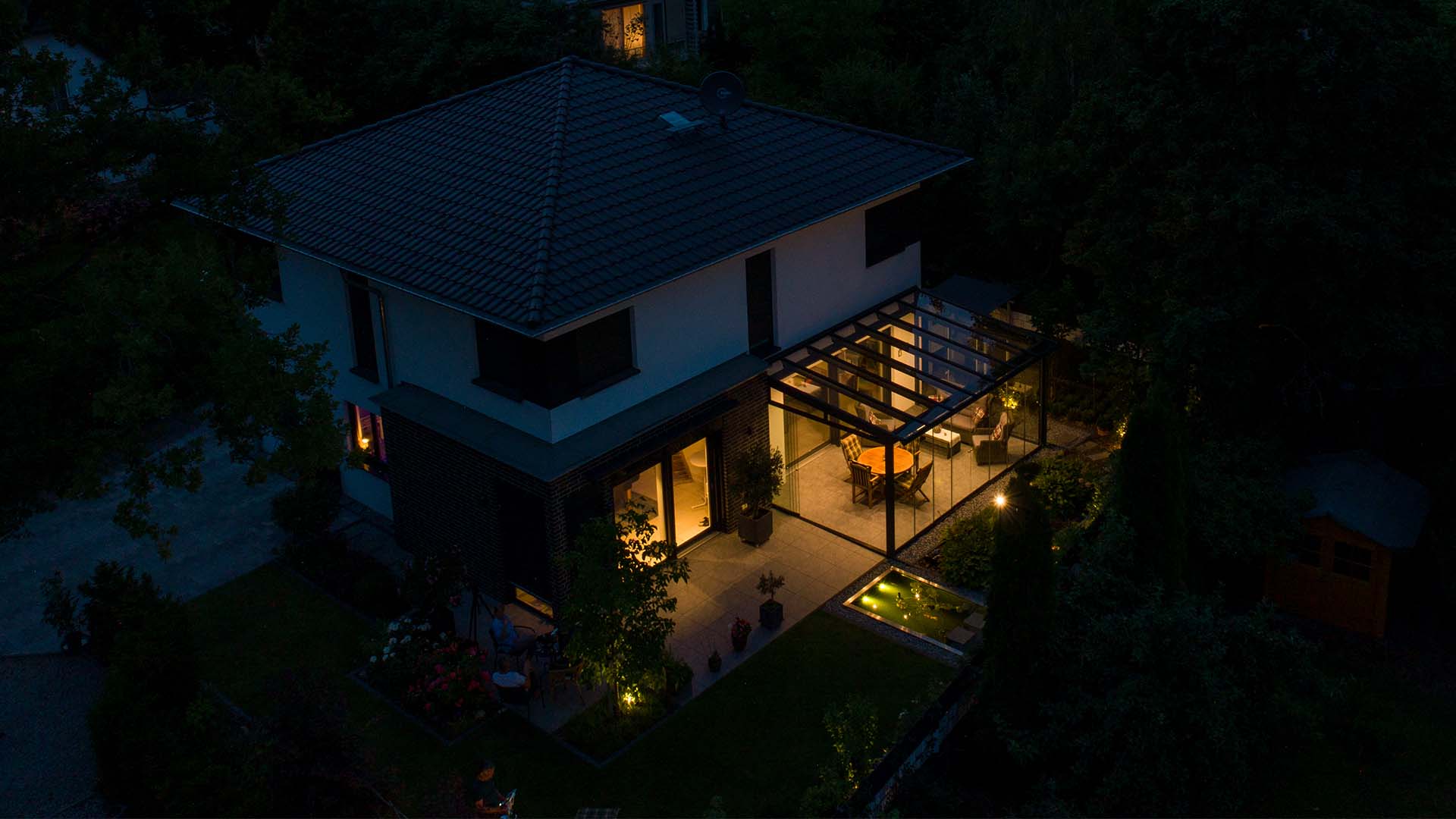 Nächtliche Atmosphäre, modernes Wohnhaus mit beleuchtetem Sommergarten