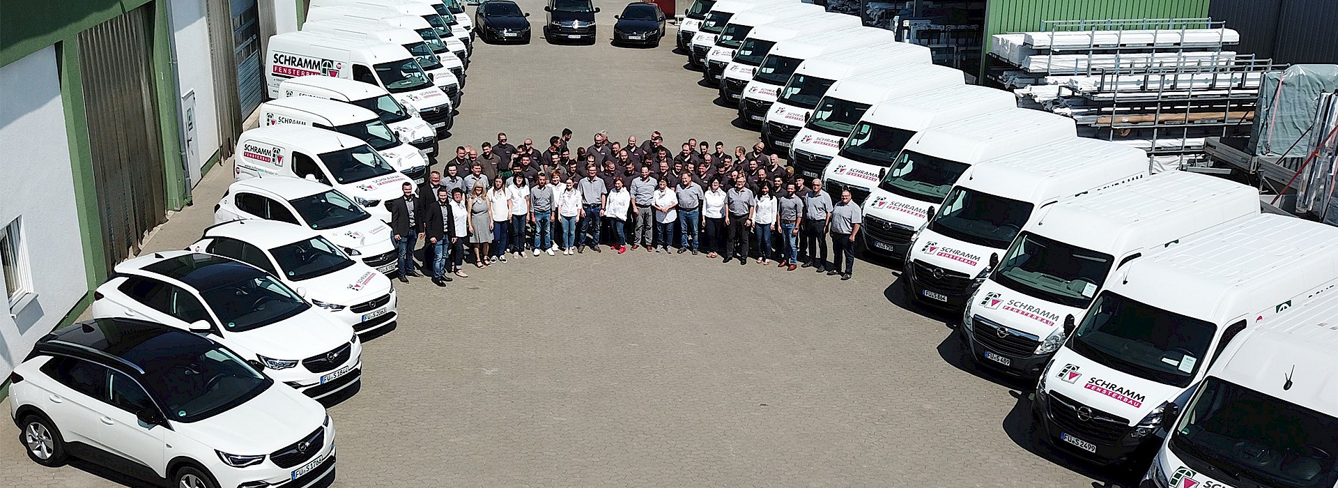 Viele weißen Autos an den Seiten und in der Mitte Mitarbeiter von Schramm Fensterbau