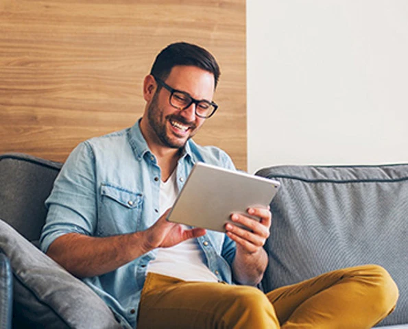 Ein Mann sitzt auf einem Sofa mit einem Tablet in der Hand