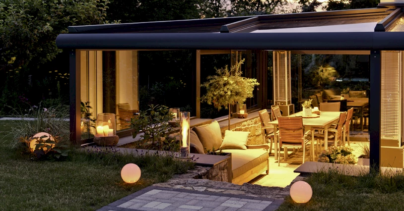 Sommergarten mit Terrasse über Eck mit Outdoor-Möbeln bei abendlicher Stimmung