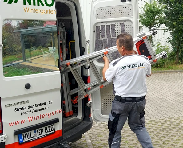 Person holt eine Leiter aus dem Auto
