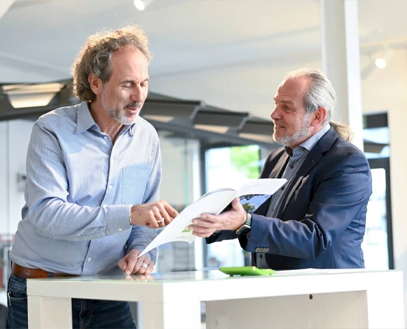 Zwei Personen unterhalten sich über ein Prospekt