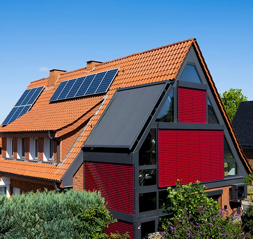 Dach eines Hauses mit einem Wintergarten an der Fassade und rote Markisen