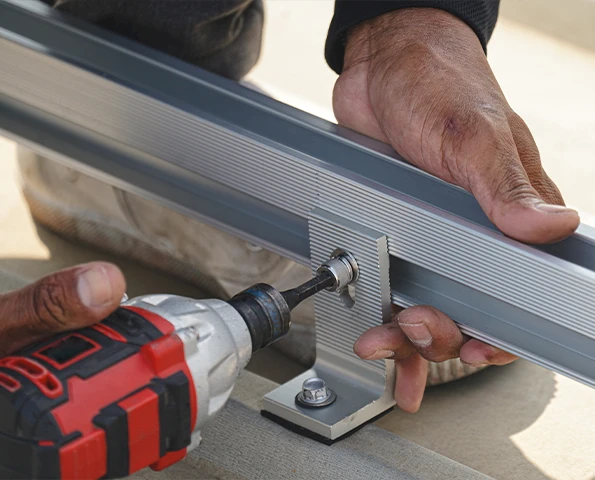 Handwerker mit Schutzhelm arbeitet konzentriert in der Werkstatt an Aluminiumprofilen, technische Präzision im Fokus.