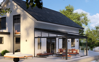 Terrassenüberdachung aus Aluminium und Glas mit gemütlicher Sitzecke, angebaut an ein modernes Einfamilienhaus.