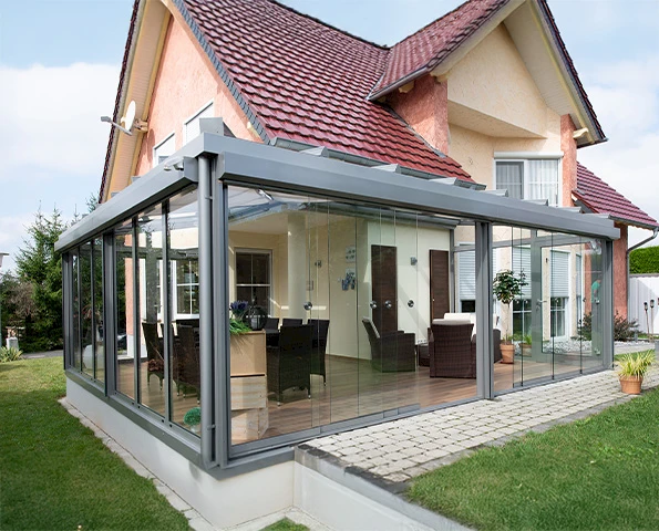 Moderner Sommergarten mit Glas-Schiebeelementen und Aluminiumrahmen, angebaut an ein Einfamilienhaus.