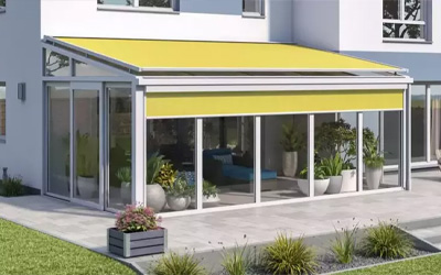 Sommergarten mit gelber Markise und Glasfront, stilvoller Übergang zwischen Innen- und Außenbereich.