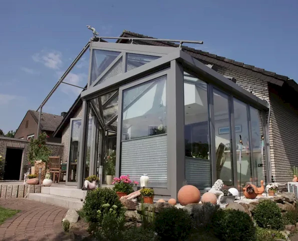 Wintergarten mit moderner Glasfassade und Aluminiumrahmen, nahtloser Übergang von Haus zu Garten.