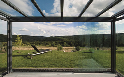 Verglaster Sommergarten mit Glasschiebewänden und Blick in die Landschaft