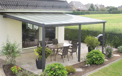 Anthrazitfarbene Terrassenüberdachung mit Glasdach, Sitzgruppe im Garten