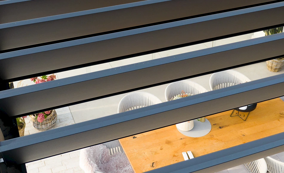 Seitenansicht modernes, weißes Wohnhaus mit einem kubischen Lamellendach und Flachdach. Sicht auf die Terrasse durch die geöffneten Lamellen.