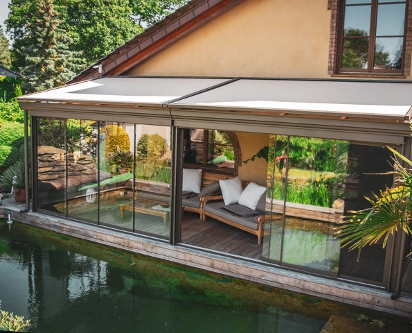 Sommergarten mit Glas-Schiebeelementen am Teich – lichtdurchfluteter Wohnraum für Garten und Terrasse.