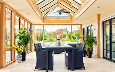 Heller Wintergarten mit Glasdach, Holzkonstruktion und stilvollem Essbereich im Grünen.