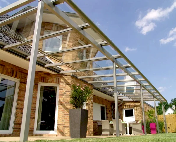 Terrassenschiebedach aus Aluminium und Glas für flexiblen Wetterschutz am Haus.
