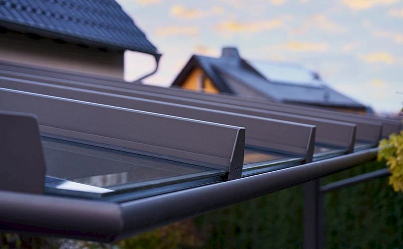 Detailansicht eines modernen Terrassendachs mit Glas und Aluminiumprofilen bei Sonnenuntergang