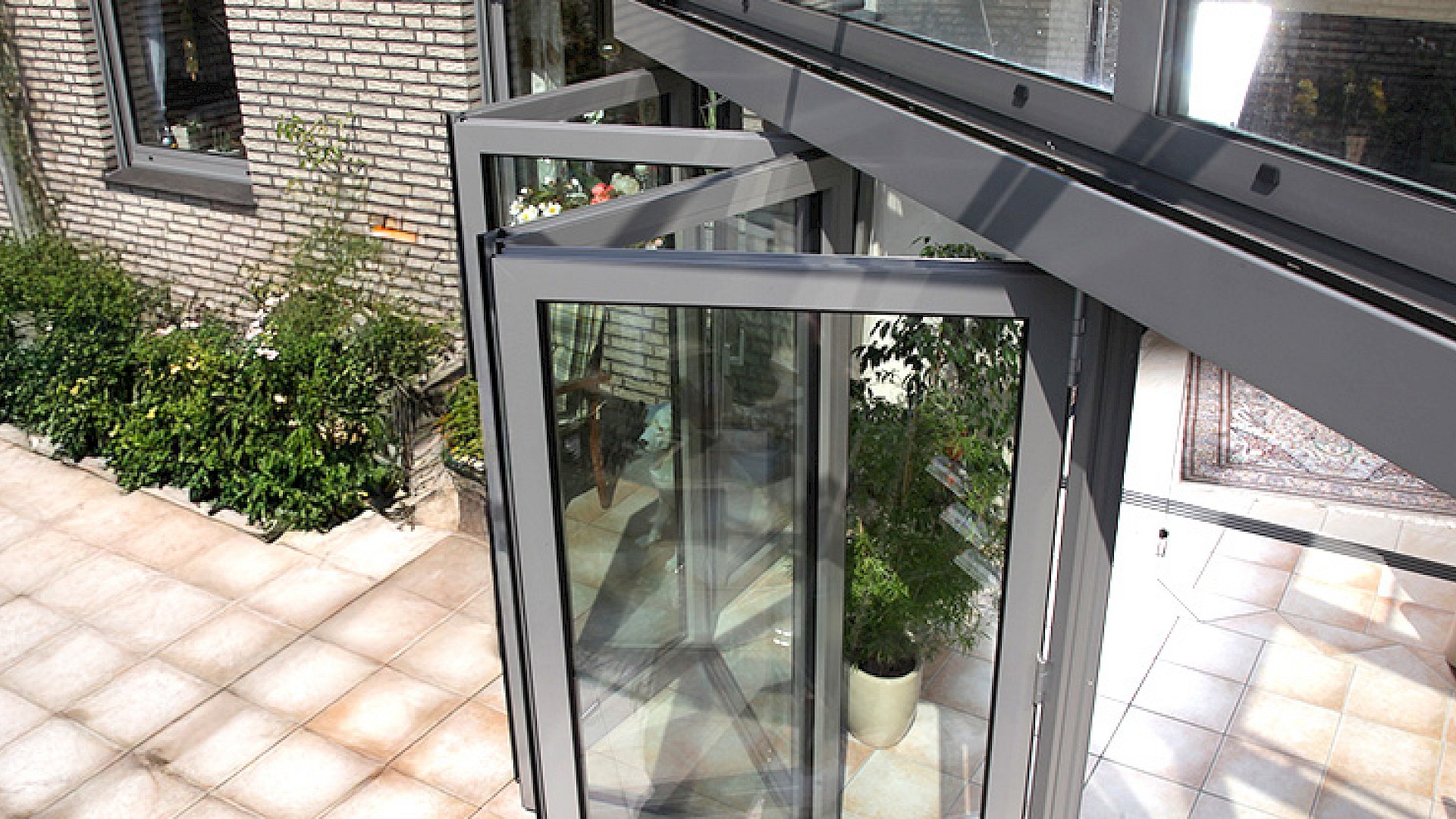 Geöffnete Faltelemente aus Glas bei einer modernen Terrassenüberdachung