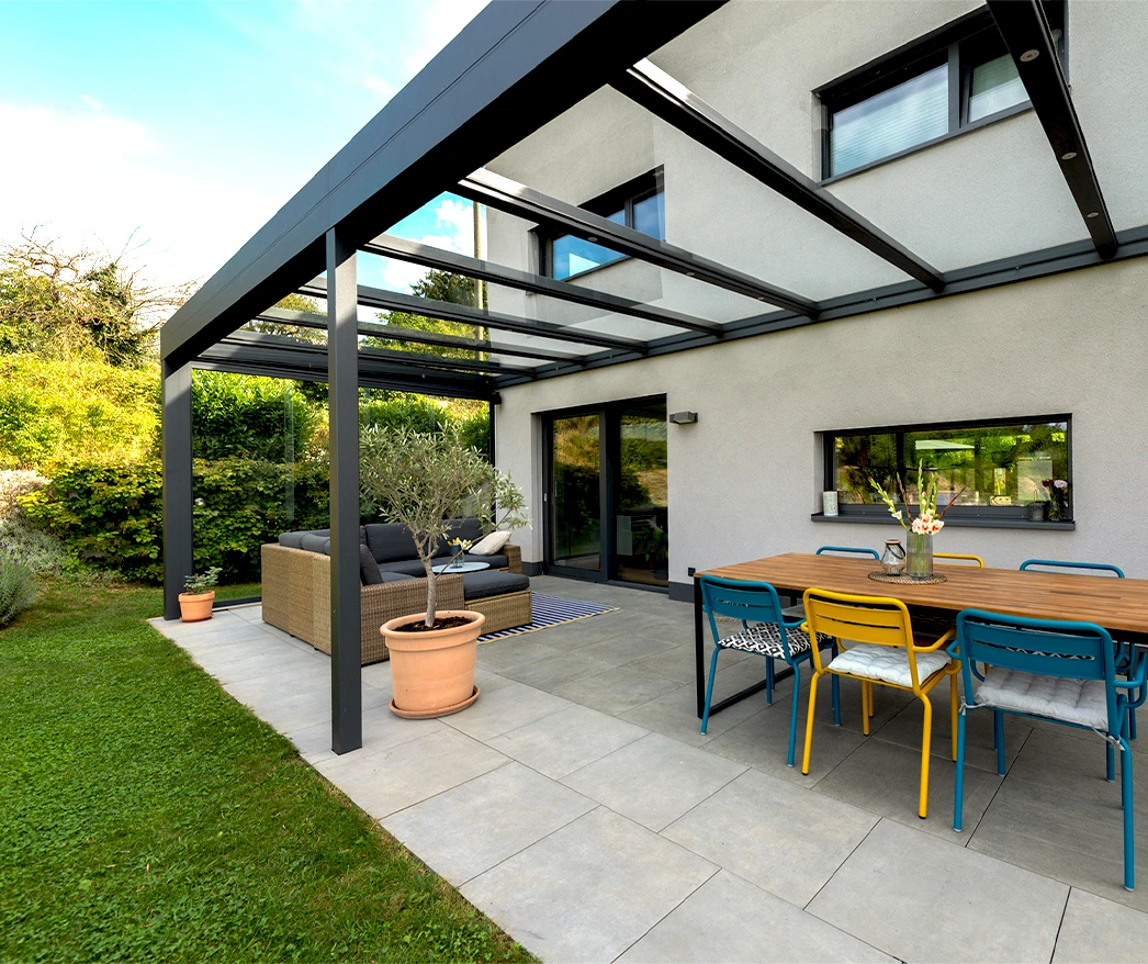 Moderne Glasüberdachung auf Terrasse mit bunten Gartenstühlen und Sitzecke