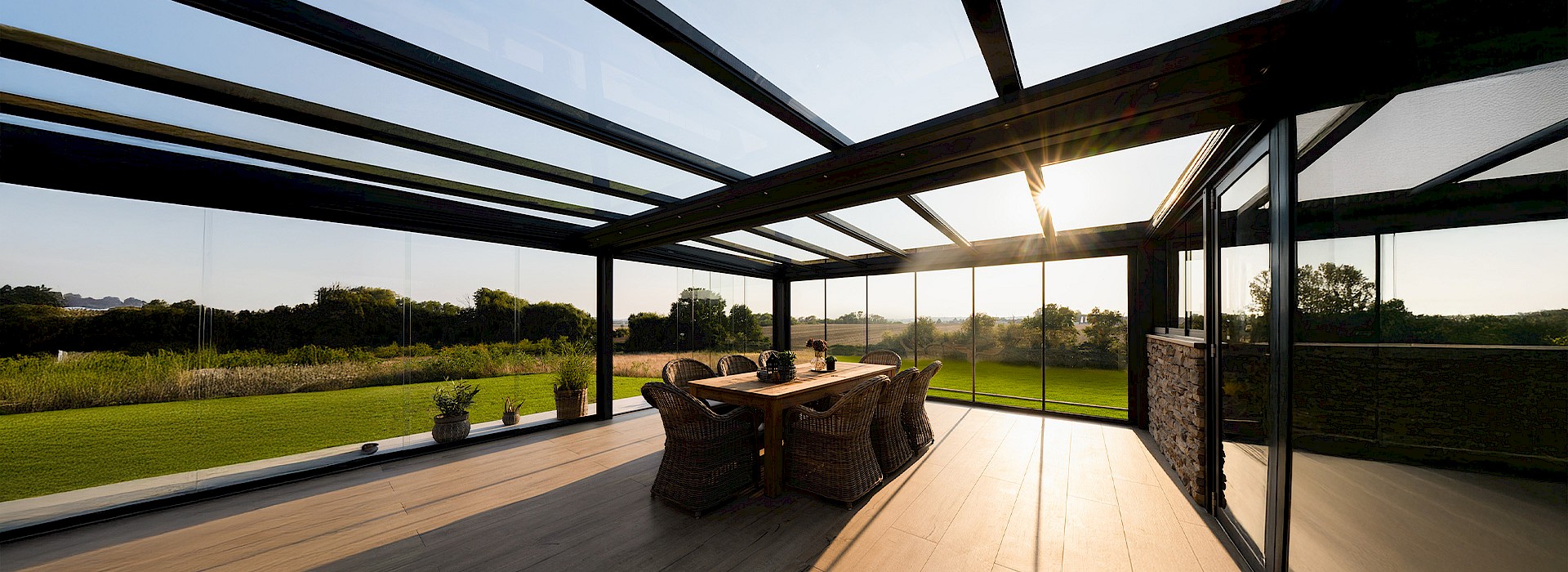 Moderne Terrassenüberdachung aus Glas und Aluminium mit Sitzbereich im Garten
