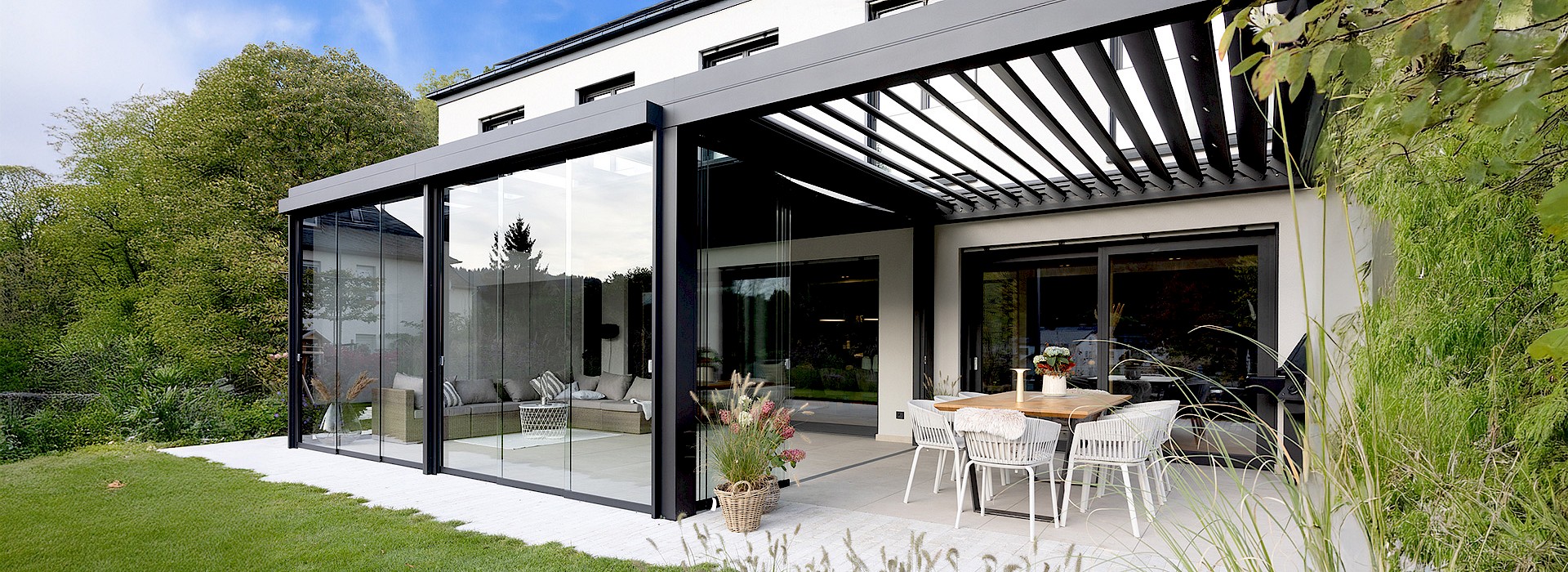Moderner Wintergarten mit Glasfront und Lamellendach als stilvolle Terrassenüberdachung