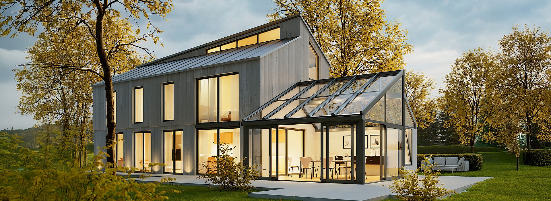 Moderner Wintergartenanbau an einem Einfamilienhaus mit großer Glasfront, stimmungsvoll beleuchtet im Garten.