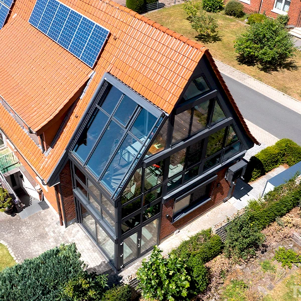 Großzügiger Wintergarten über zwei Etagen mit schwarzer Aluminiumkonstruktion und Glasfassade.