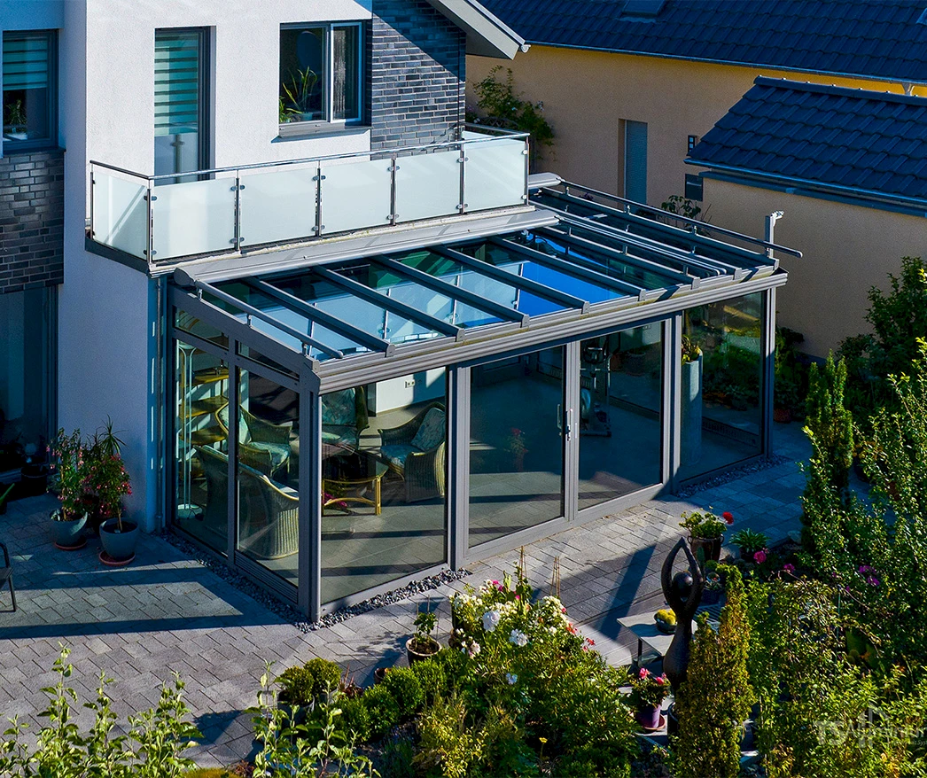 Flachdach-Wintergarten mit Glasfronten und integriertem Balkon an einem modernen Einfamilienhaus.