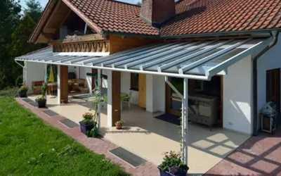 Klassische Terrassenüberdachung mit Glasdach und weißer Aluminiumkonstruktion, harmonisch integriert ins Hausdesign.