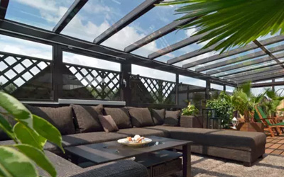 Wintergarten mit Glasdach und Loungeecke, geschützter Wohnbereich mit Gartenblick.