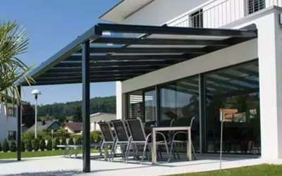 Moderne Terrassenüberdachung mit Glasdach und Essbereich, elegante Verbindung von Haus und Garten.