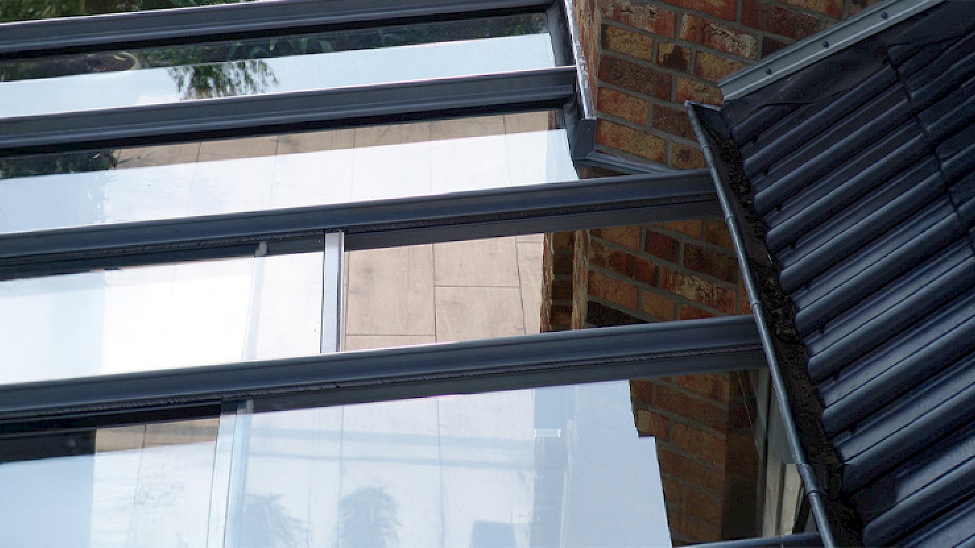 Detailaufnahme einer Terrassenüberdachung mit Glasdach und integrierter Belüftung am Hausanschluss