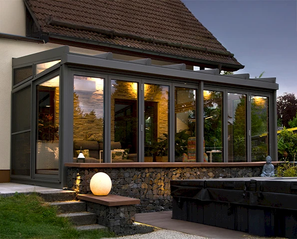 Wintergarten mit moderner Glasfassade und Aluminiumrahmen, nahtloser Übergang von Haus zu Garten.