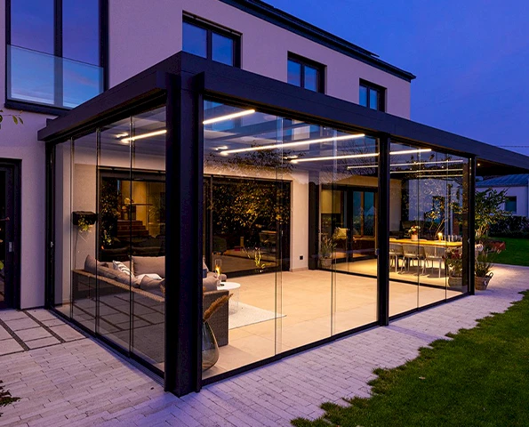 Terrassenüberdachung mit integrierter LED-Beleuchtung am Abend, gemütlicher Essbereich im Außenbereich.