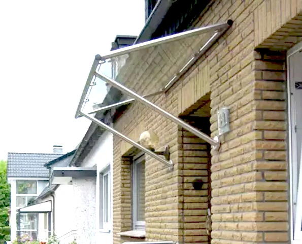 Glasvordach mit Edelstahlträgern über Eingangstür, stilvoller Wetterschutz mit klarer Linienführung.