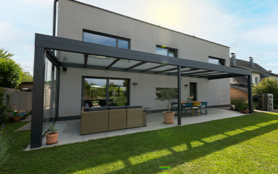 Großes Terrassendach aus Aluminium mit Glasdach an einem modernen Wohnhaus und großzügigem Gartenbereich.