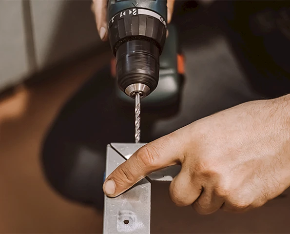 Handwerker bohrt präzise in Aluminiumprofil, Montagearbeit im Metallbau mit Akkubohrmaschine.