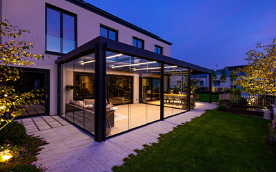 Verglaster Sommergarten mit LED-Beleuchtung bei Abendstimmung an einem modernen Stadthaus.