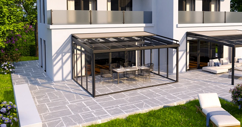 Sommergarten mit außenliegendem Sonnenschutz in dezentem Grau, großzügig verglast und mit stilvollem Esstisch und schwarzen Stühlen ausgestattet.