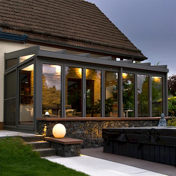 Moderner Wintergarten als separater Wohnraum mit Glasfassade und stimmungsvoller Beleuchtung am Abend.