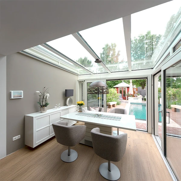 Wintergarten als elegante Verlängerung des Wohnraums mit Glasdach und Blick auf den Garten mit Pool.