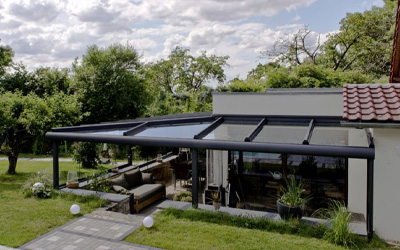 Glas-Terrassenüberdachung mit seitlichem Windschutz als gemütlicher Außenbereich