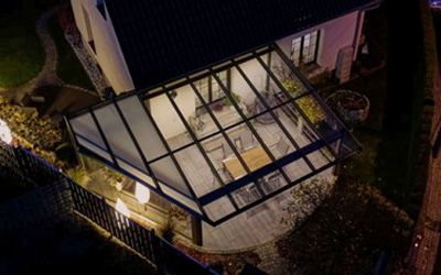 Wintergarten mit Glasüberdachung in moderner Architektur bei Nacht beleuchtet