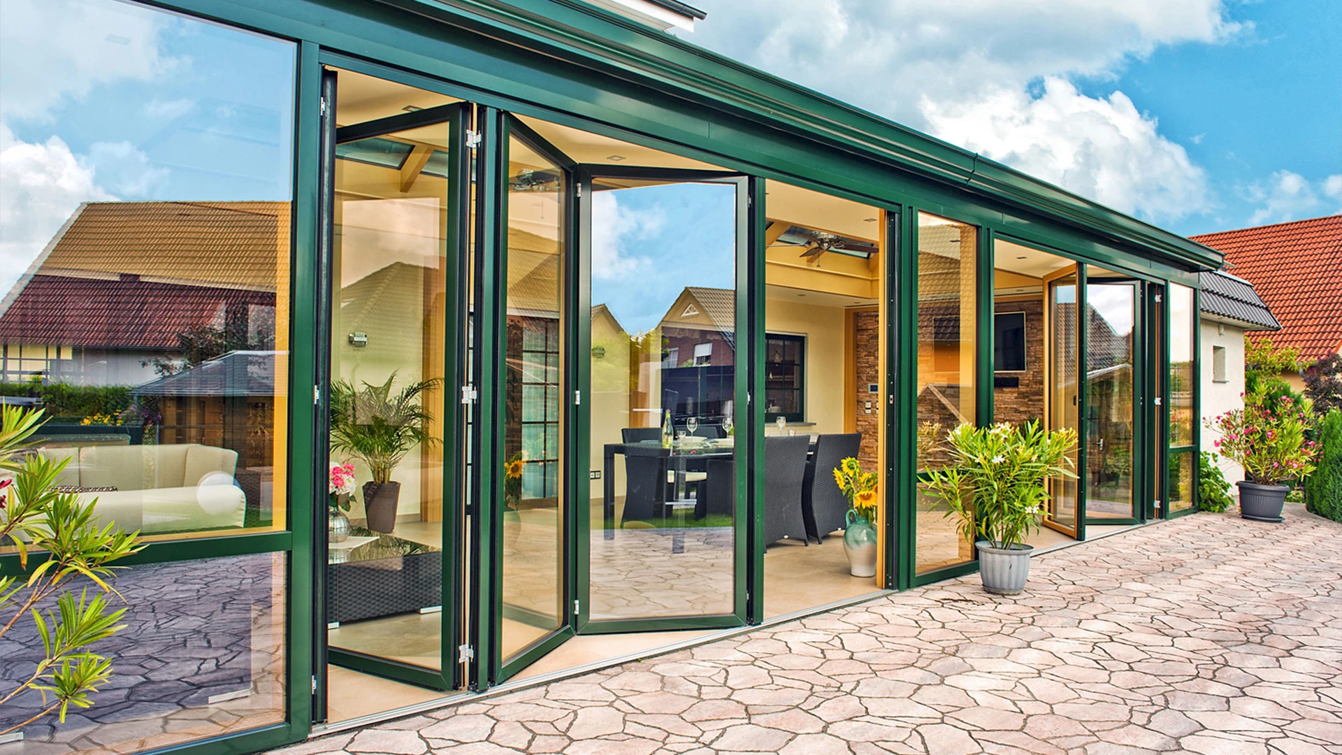 Moderner Wintergarten mit grüner Aluminium-Faltanlage und Glasfront für lichtdurchflutetes Wohnen.