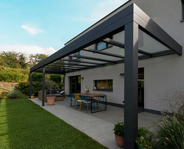 Elegantes Terrassendach aus Aluminium und Glas für stilvolle Outdoor-Lounge und Essbereich im Garten.