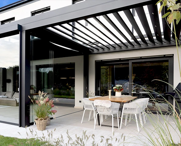 Modernes Lamellendach mit Glaswänden als stilvolle Terrassenüberdachung für ganzjährigen Wetterschutz.