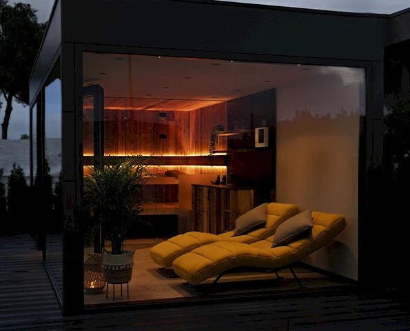 Exklusiver Modulraum mit Glasfront und gemütlicher Innenausstattung als moderner Rückzugsort im Garten.