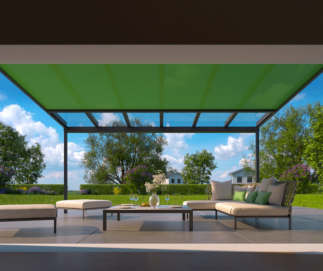 Blick aus einem Wintergarten mit grüner Unterglasmarkise auf den sonnigen Garten mit Sitzmöglichkeiten und Blumen.